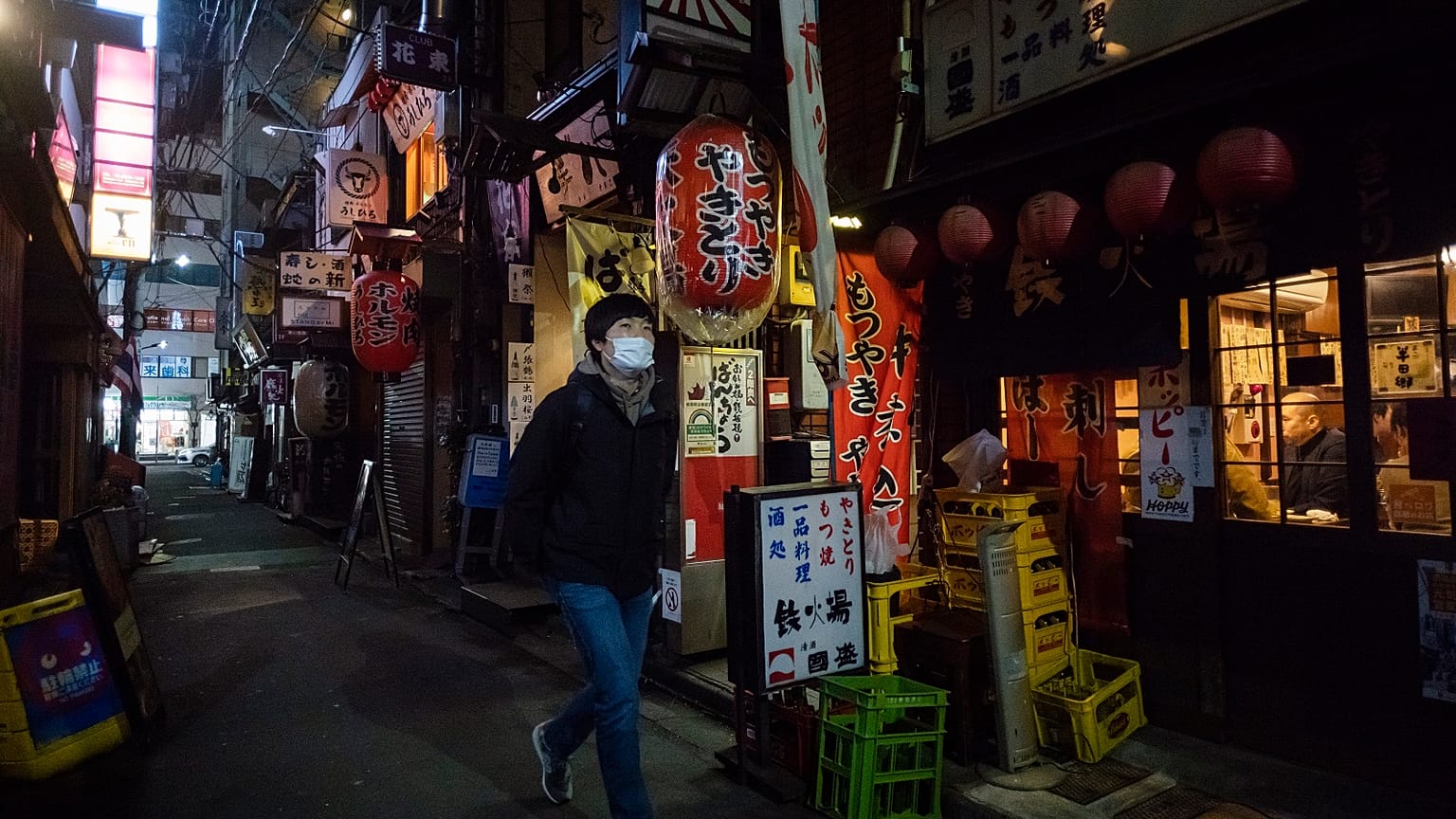 A man walks through an alley filled with restaurants and bars after 8 p.m. on the first day of a coronavirus state of emergency in Tokyo on Friday, Jan. 8, 2021.