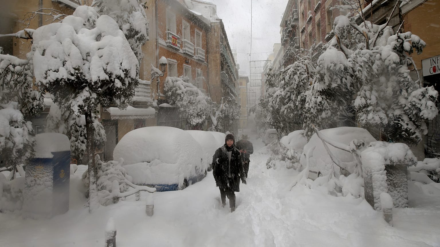 People walk during a heavy snowfall in Madrid, Spain, Saturday, Jan. 9, 2021