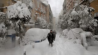 People walk during a heavy snowfall in Madrid, Spain, Saturday, Jan. 9, 2021