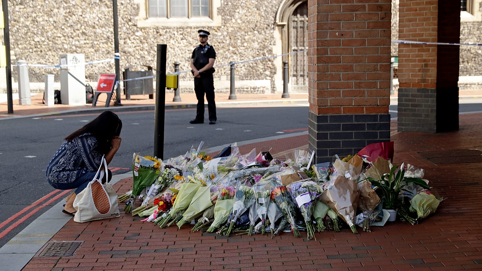 A woman reacts after placing flowers by a police cordon near the scene of a fatal multiple stabbing attack at the Forbury Gardens park, in Reading, England, June 23, 2020.