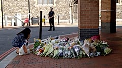 A woman reacts after placing flowers by a police cordon near the scene of a fatal multiple stabbing attack at the Forbury Gardens park, in Reading, England, June 23, 2020.