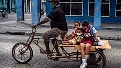 Un hombre lleva a tres niños en su triciclo en La Habana, Cuba