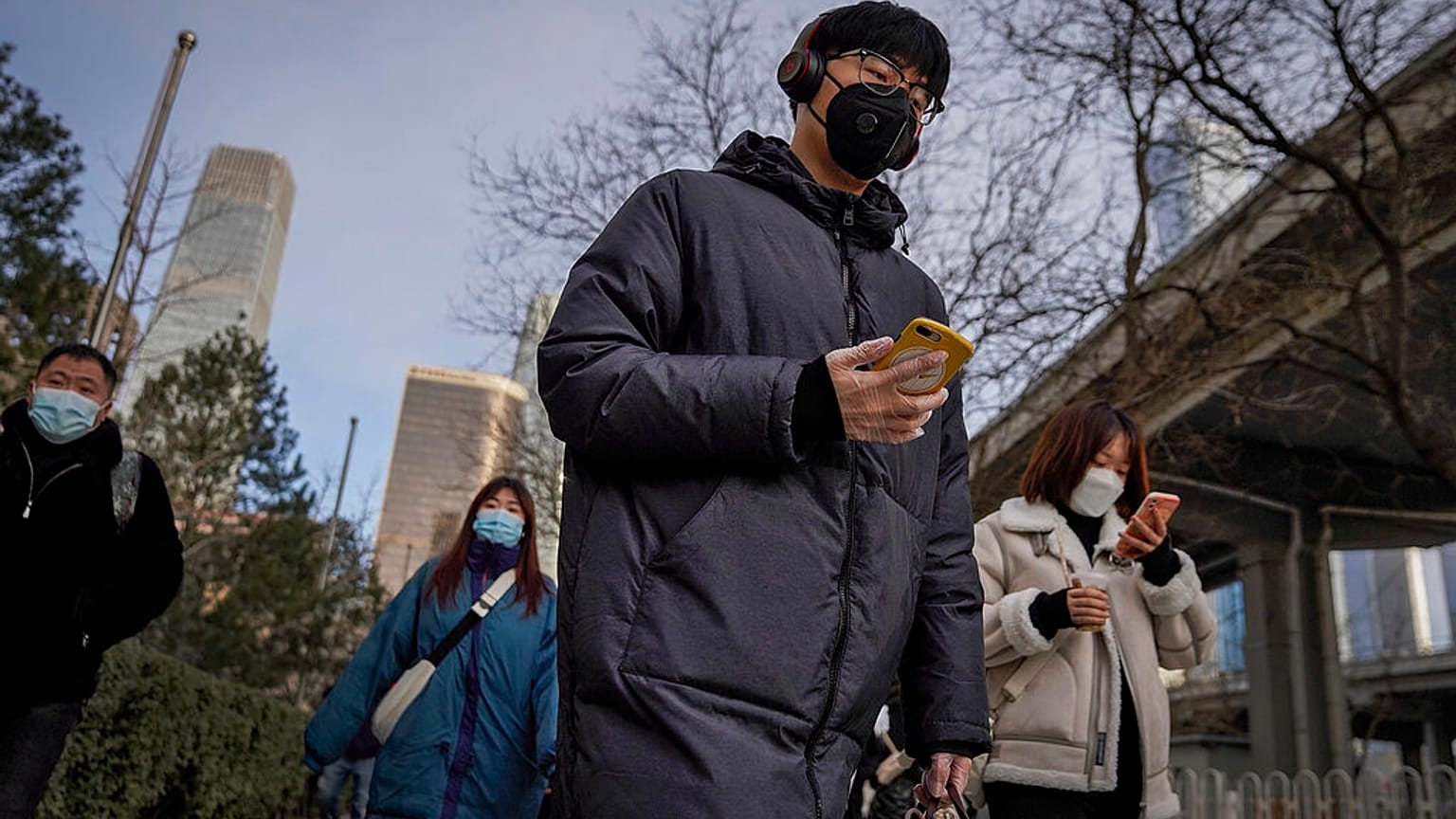 A man wearing a face mask and a disposable gloves to help curb the spread of the coronavirus heads to work with other masked people during the morning rush hour in Beijing.