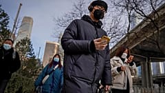 A man wearing a face mask and a disposable gloves to help curb the spread of the coronavirus heads to work with other masked people during the morning rush hour in Beijing.