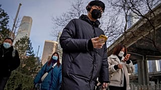 A man wearing a face mask and a disposable gloves to help curb the spread of the coronavirus heads to work with other masked people during the morning rush hour in Beijing.