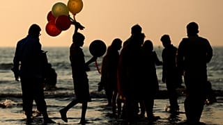 صبي يبيع بالونات على شاطئ جوهو في مومباي في الهند. 2020/12/26