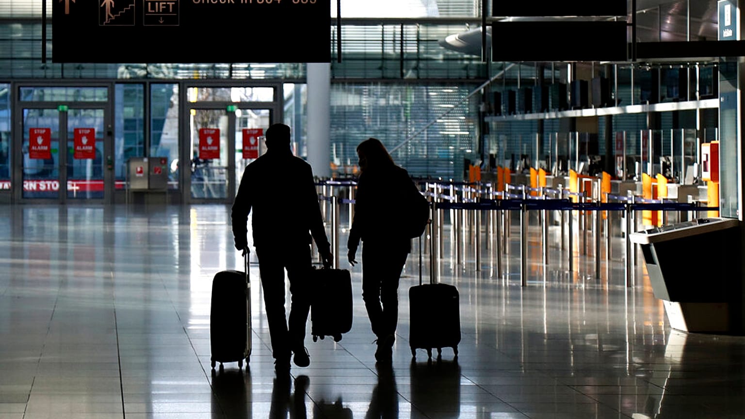 In this Saturday, Dec. 26, 2020 file photo, people walk with their luggage through a deserted check-in hall at the airport in Munich, Germany