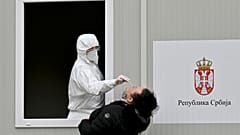 A medical worker takes a sample with a swab from a woman, during a coronavirus test, at the Institute of Virology, Vaccines and Sera “Torlak” in Belgrade on December 24, 2020