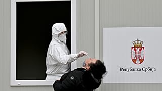 A medical worker takes a sample with a swab from a woman, during a coronavirus test, at the Institute of Virology, Vaccines and Sera “Torlak” in Belgrade on December 24, 2020