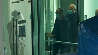 Passengers arriving on the flight from Singapore are processed by staff in protective clothings and directed towards a covered walkway to a separate exit from the airport.