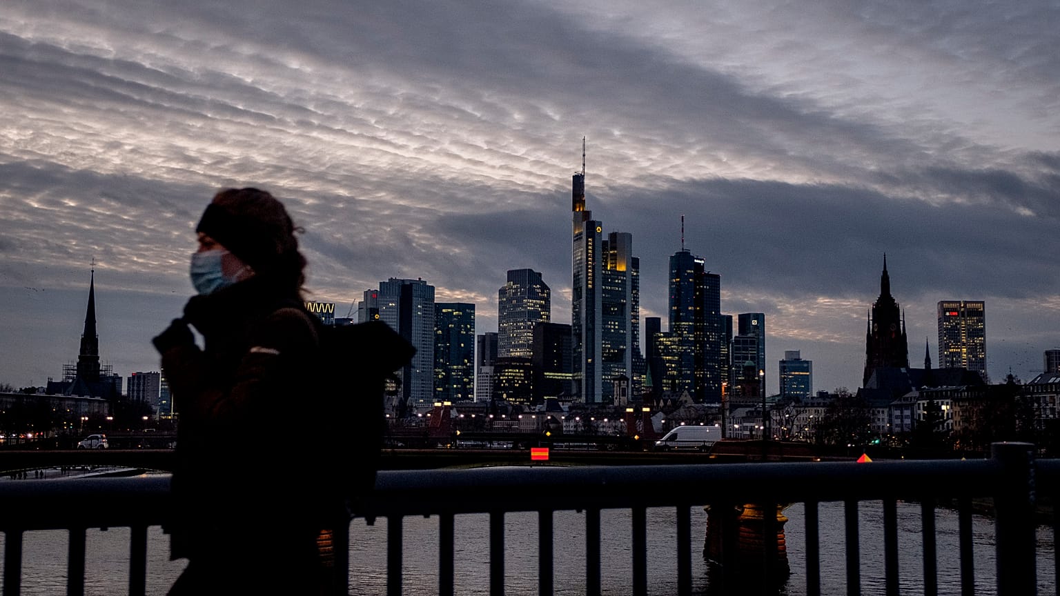 Frau mit Maske vor der Frankfurter Skyline. 