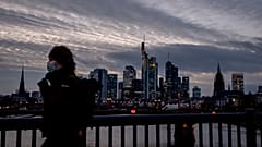 Frau mit Maske vor der Frankfurter Skyline. 