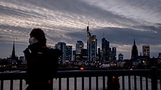 Frau mit Maske vor der Frankfurter Skyline. 