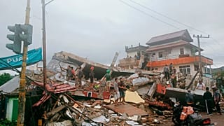 Residents inspect earthquake-damaged buildings in Mamuju, West Sulawesi, Indonesia, Friday, Jan. 15