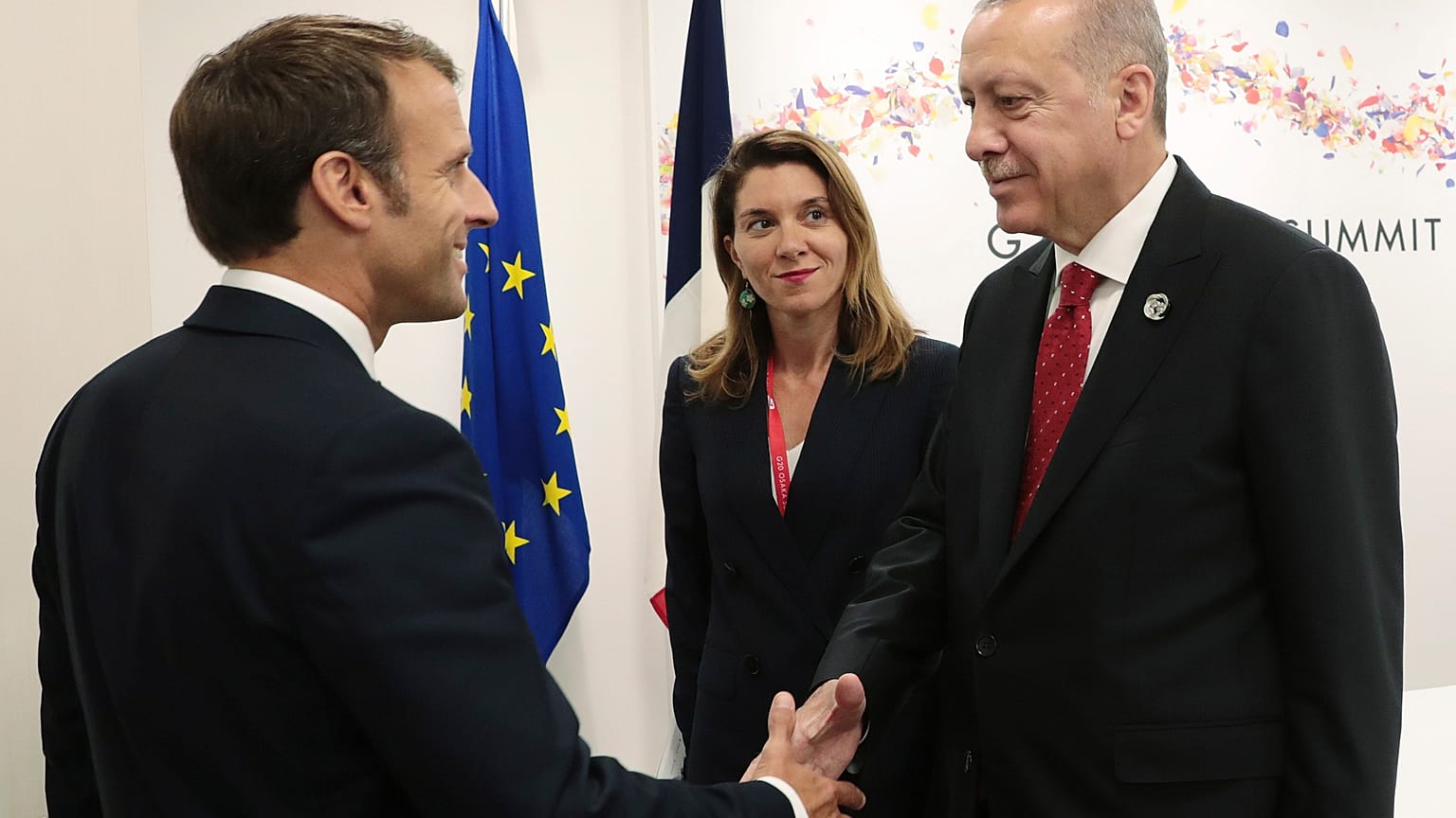 الرئيس التركي رجب طيب أردوغان يصافح الرئيس الفرنسي إيمانويل ماكرون خلال قمة مجموعة العشرين في أوساكا، اليابان. 