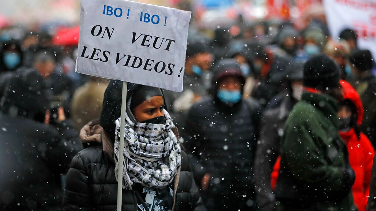 Paris'te gösterilere katılan bir vatandaş. Taşıdığı parnkatta "Videoları istiyoruz" yazıyor.
