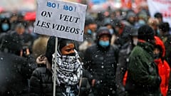 Paris'te gösterilere katılan bir vatandaş. Taşıdığı parnkatta "Videoları istiyoruz" yazıyor.