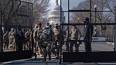 Members of the National Guard change shifts as they exit through anti-scaling security fencing on Saturday, Jan. 16, 2021, in Washington.