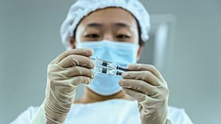 Kínai egészségügyi dolgozó nézi a Sinopharm vakcinájával