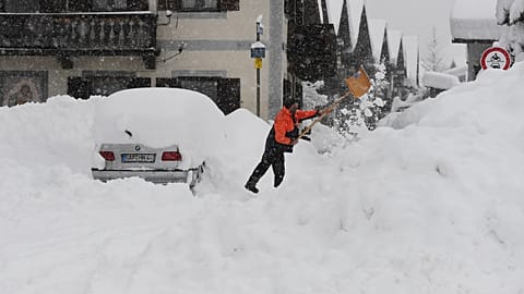 A man shovels his car free of snow after days of snowfall in Garmisch-Partenkirchen, southern Germany, Monday, Jan. 18, 2021.
