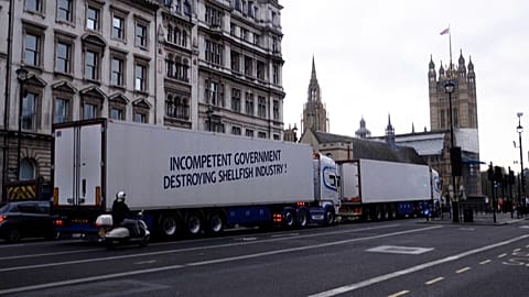 Lorry with ‘Incompetent government destroying shellfish industry’ waiting at a red light with Westminster in the background