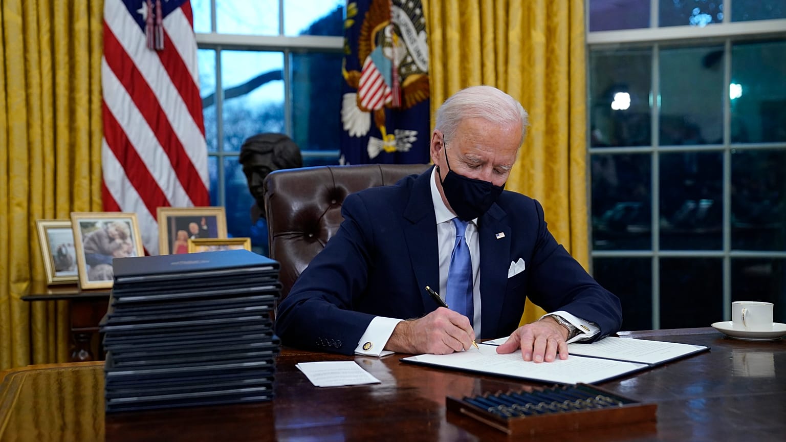 President Joe Biden signs his first executive order in the Oval Office of the White House on Wednesday, Jan. 20, 2021, in Washington.