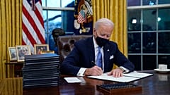President Joe Biden signs his first executive order in the Oval Office of the White House on Wednesday, Jan. 20, 2021, in Washington.
