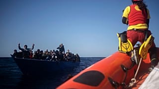 Migrants are assisted by aid workers of the Spanish NGO Open Arms, after fleeing Libya on board a precarious wooden boat in the Mediterranean Sea, Jan. 2, 2021.