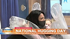 Two people hug through a plastic hugging curtain