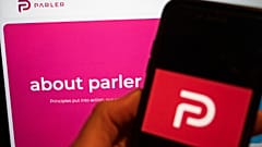 The logo of the social media platform Parler is displayed in Berlin, Jan. 10, 2021. In the background on a screen is the platform's website.