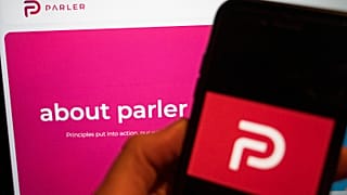 The logo of the social media platform Parler is displayed in Berlin, Jan. 10, 2021. In the background on a screen is the platform's website.