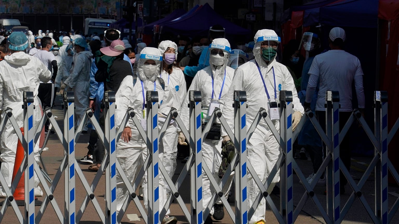 Trabajadores del gobierno con equipo de protección personal caminan en el área cerrada en el distrito de Jordan en Hong Kong, el sábado 23 de enero de 2021. 