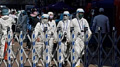 Trabajadores del gobierno con equipo de protección personal caminan en el área cerrada en el distrito de Jordan en Hong Kong, el sábado 23 de enero de 2021. 