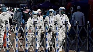 Trabajadores del gobierno con equipo de protección personal caminan en el área cerrada en el distrito de Jordan en Hong Kong, el sábado 23 de enero de 2021.
