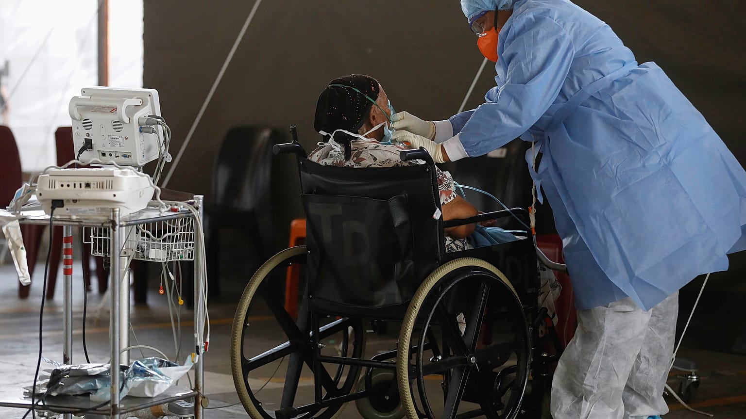 Um profissional de saúde usando equipamento de proteção individual (EPI) fornece oxigênio a um paciente.