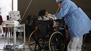Um profissional de saúde usando equipamento de proteção individual (EPI) fornece oxigênio a um paciente.