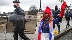 Eine als "Marianne" gekleidete Demonstrantin, dem Symbol der französischen Republik seit 1789, läuft neben Polizeibeamten bei einem "Marsch für die Freiheit", 23.01.21 