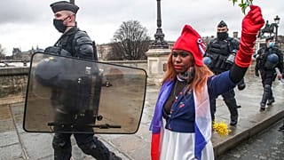 Eine als "Marianne" gekleidete Demonstrantin, dem Symbol der französischen Republik seit 1789, läuft neben Polizeibeamten bei einem "Marsch für die Freiheit", 23.01.21