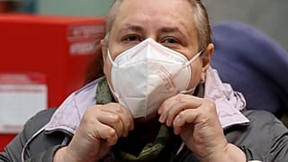 Uma mulher ajusta uma máscara protetora FFP2 ao fazer compras num supermercado em Viena, Áustria.