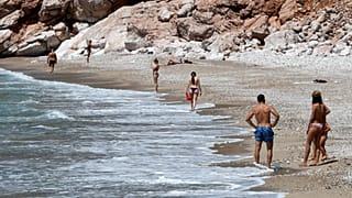 People walk on a beach near the town of Budva, on the Adriatic coast of Montenegro, on May 13, 2020.