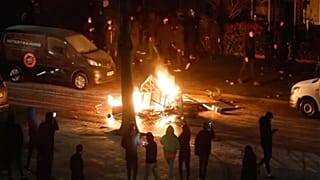 In this grab taken from video on Monday, Jan, 25, 2021, people use their phones to film items burning on a fire started by rioters, in Haarlem, Netherlands. 