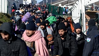 Police officers stand by migrants as they leave to be relocated from the Lipa camp northwestern Bosnia, near the border with Croatia, Bosnia, Tuesday, Dec. 29, 2020. 
