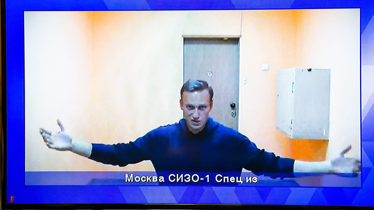 Navalny appears on a TV screen during a live session with the court 
