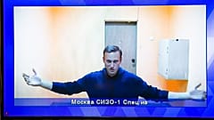 Navalny appears on a TV screen during a live session with the court 