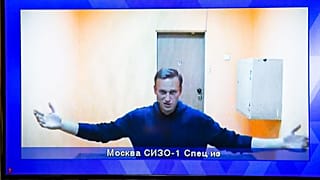 Navalny appears on a TV screen during a live session with the court 