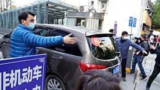 A car that's part of a convoy carrying the World Health Organization team of researchers arrives at the Hubei Province Xinhua Hospital in Wuhan on Friday, Jan. 29.
