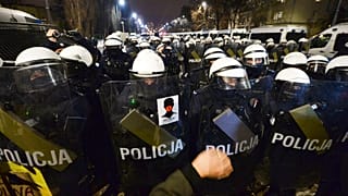 A Nők Sztrájkja matricája egy rendőr pajzsán Varsóban