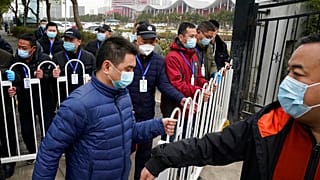 Security personnel move a barrier to clear the way for the World Health Organization team as they depart from the Wuhan Jinyintan Hospital after a field visit in Wuhan