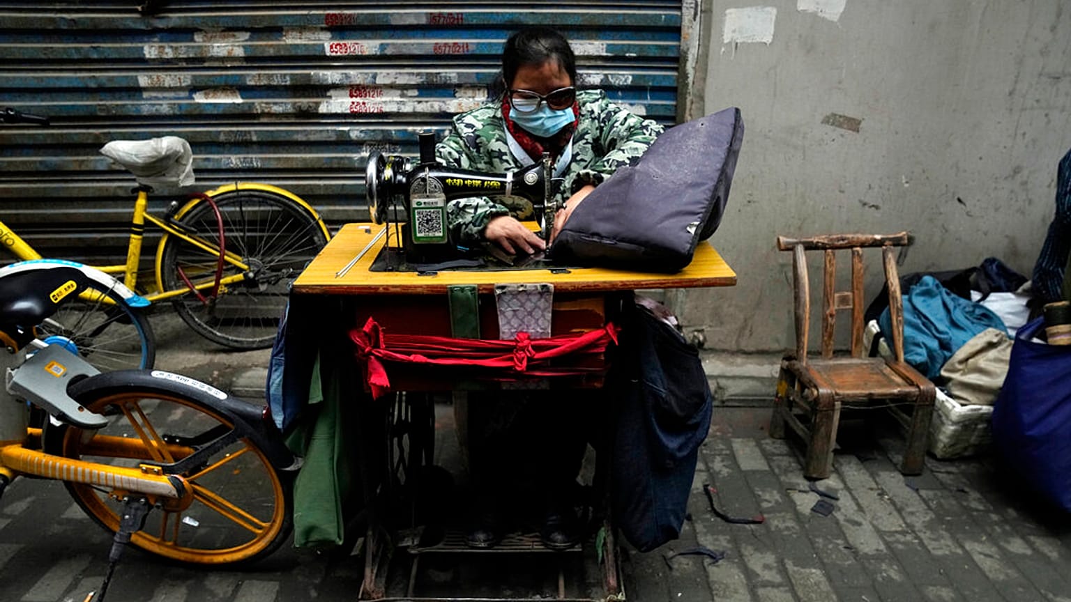 A seamstress wears a mask to protect from coronavirus as she sews zippers along an alleyway in Wuhan in central China's Hubei province, Jan. 22, 2021.
