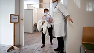  In this Jan. 18, 2021, file photo, a woman is guided to a vaccination booth prior to receiving the vaccination against COVID-19 at a vaccination center in Saint Denis